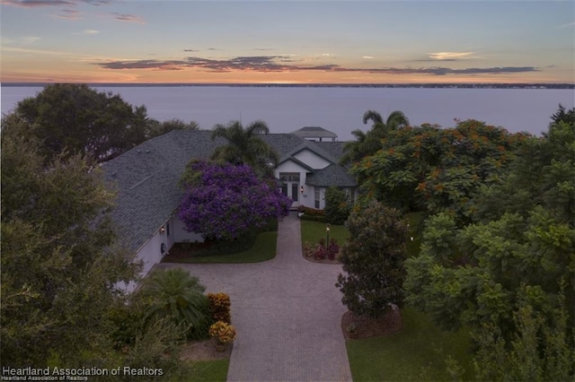 aerial view at dusk featuring a water view