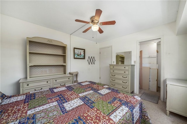 bedroom featuring a walk in closet, light colored carpet, and ceiling fan