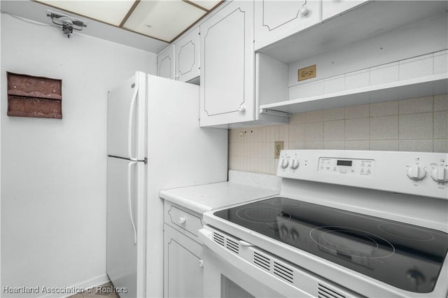 kitchen featuring tasteful backsplash, white cabinetry, white refrigerator, and range