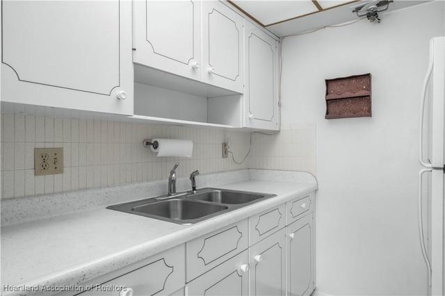 kitchen featuring white cabinets, white fridge, sink, and backsplash