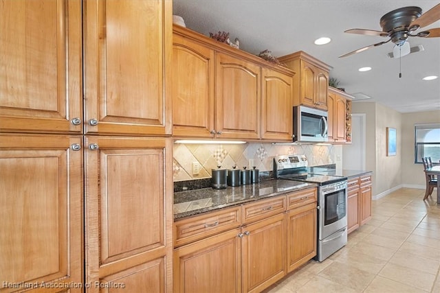 kitchen featuring ceiling fan, appliances with stainless steel finishes, light tile patterned floors, dark stone countertops, and decorative backsplash