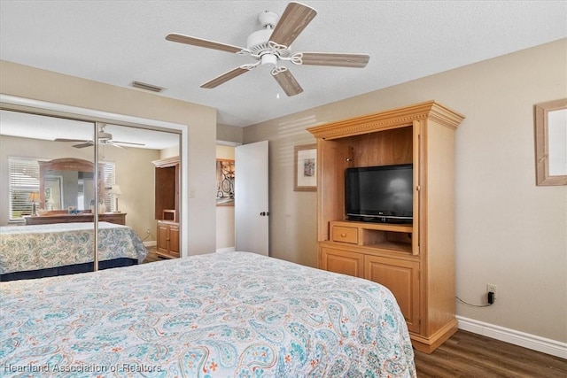 bedroom with a textured ceiling, a closet, ceiling fan, and dark hardwood / wood-style flooring