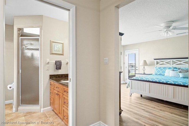 bedroom featuring a textured ceiling, ensuite bathroom, and ceiling fan