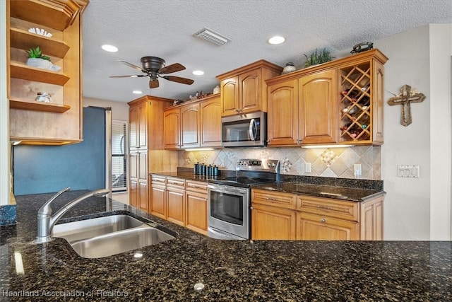 kitchen with a textured ceiling, stainless steel appliances, tasteful backsplash, sink, and ceiling fan