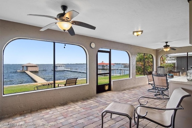 sunroom with ceiling fan, a water view, and plenty of natural light