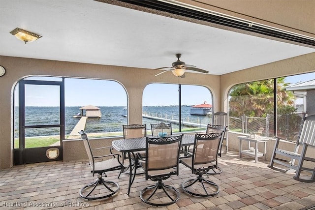 sunroom / solarium with ceiling fan, plenty of natural light, and a water view