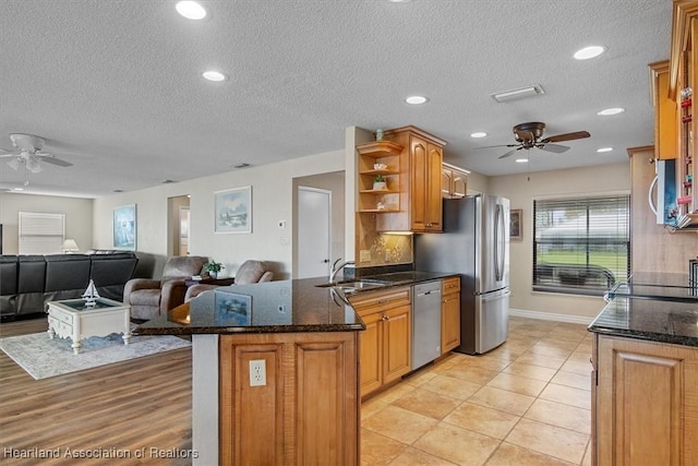 kitchen featuring sink, dark stone countertops, ceiling fan, and stainless steel appliances