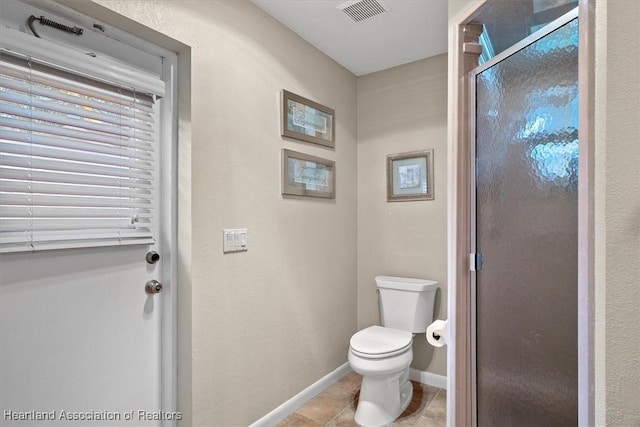 bathroom featuring a shower with shower door, tile patterned floors, and toilet