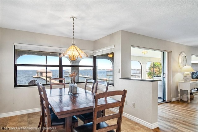 dining space featuring a chandelier, a textured ceiling, and a water view