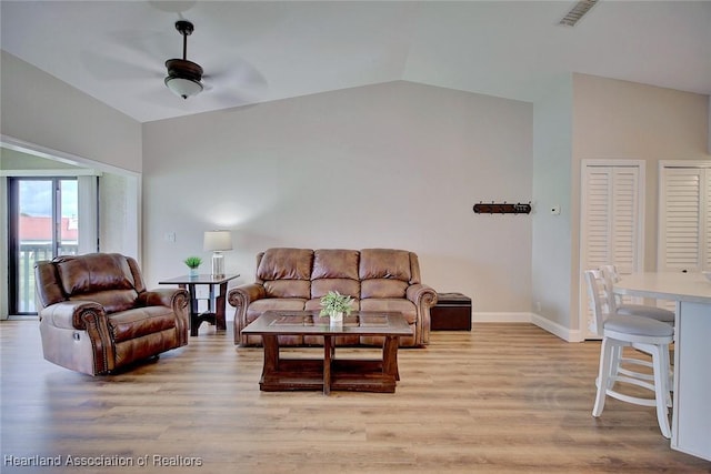 living room featuring ceiling fan, light hardwood / wood-style floors, and lofted ceiling