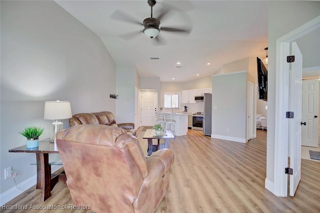 living room featuring ceiling fan, light wood-type flooring, and vaulted ceiling