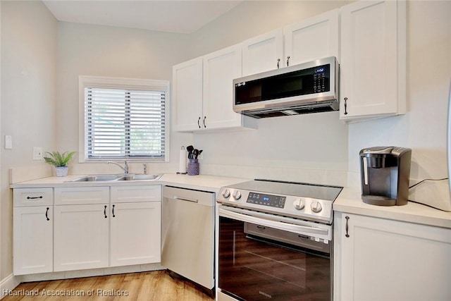 kitchen with white cabinetry, sink, stainless steel appliances, and light hardwood / wood-style flooring