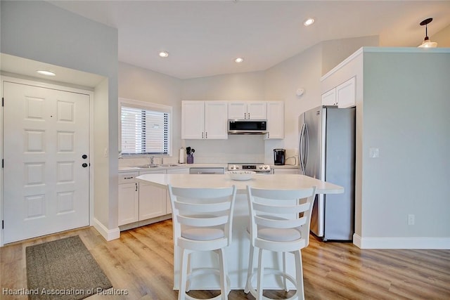 kitchen with a center island, sink, appliances with stainless steel finishes, light hardwood / wood-style floors, and white cabinetry