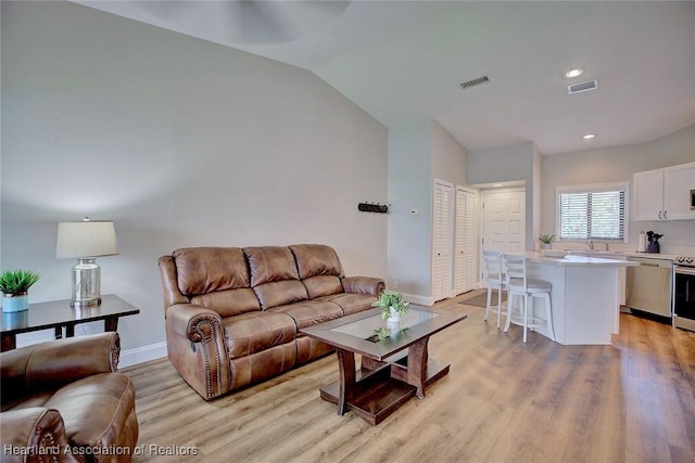 living room with light hardwood / wood-style floors, lofted ceiling, and sink