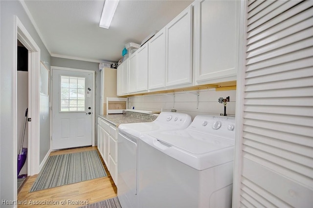 laundry room featuring cabinets, light hardwood / wood-style floors, washer and clothes dryer, and crown molding