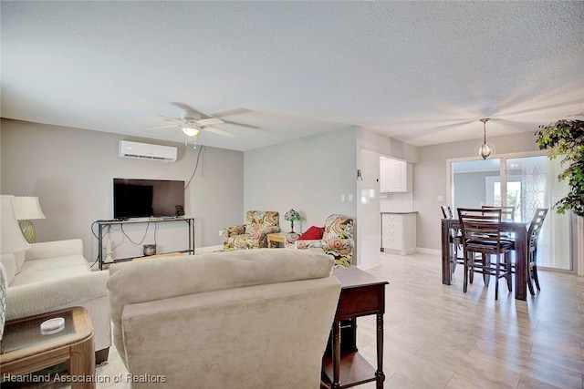 living room with ceiling fan, an AC wall unit, and a textured ceiling