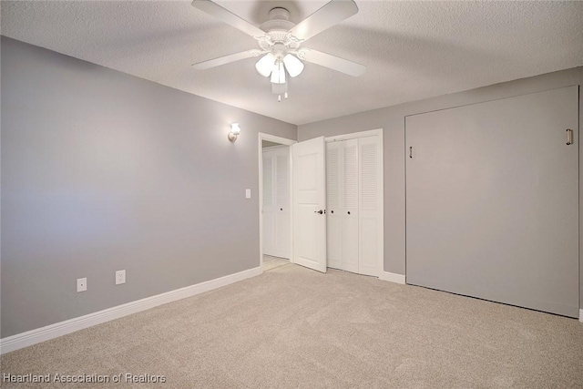 unfurnished bedroom with a textured ceiling, ceiling fan, light carpet, and a closet