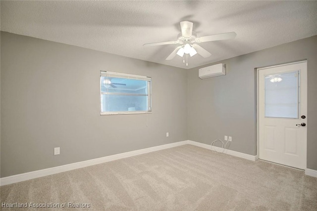 spare room with a textured ceiling, light colored carpet, a wall mounted AC, and ceiling fan