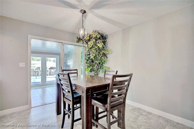 tiled dining area with french doors and a textured ceiling