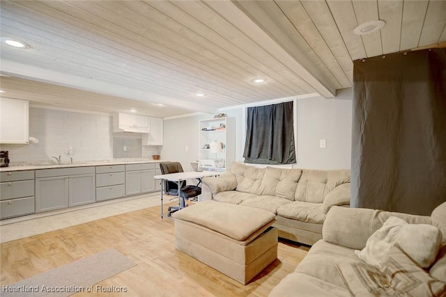 living room featuring beamed ceiling, light hardwood / wood-style floors, wooden ceiling, and sink