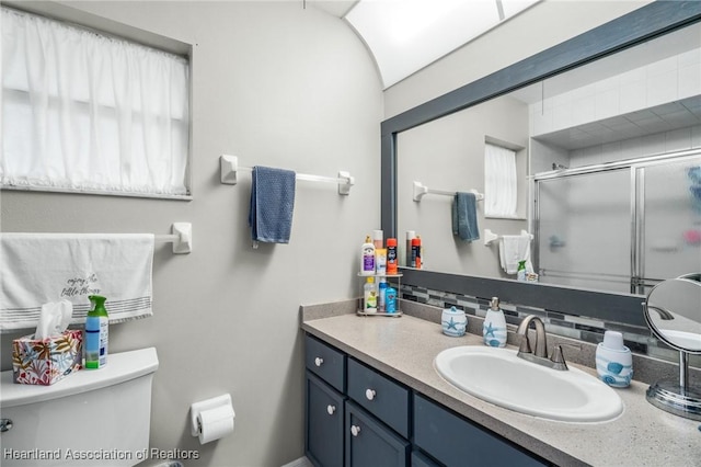 bathroom with vanity, toilet, and a shower with door