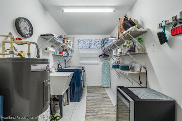 laundry room with light tile patterned flooring, washing machine and dryer, and water heater