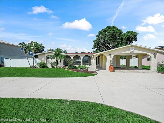 view of front facade with a front lawn, a gate, curved driveway, and stucco siding