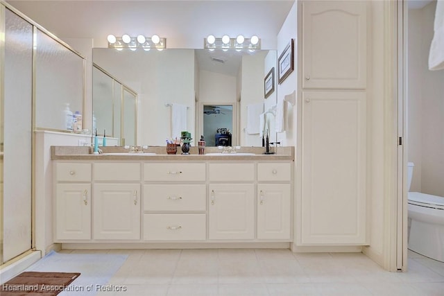 bathroom with toilet, vanity, an enclosed shower, and tile patterned flooring