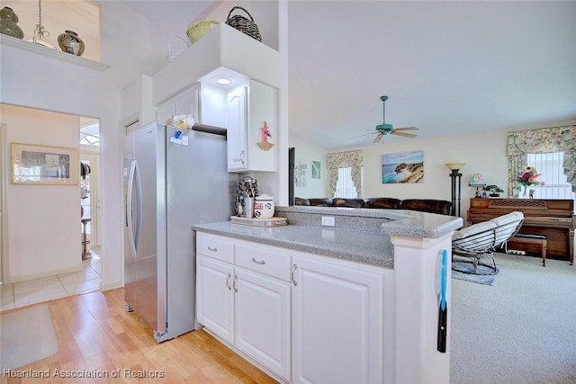 kitchen featuring white cabinets, light hardwood / wood-style floors, stainless steel fridge, kitchen peninsula, and ceiling fan