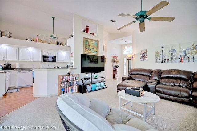 living room featuring light wood-type flooring, ceiling fan, and a high ceiling