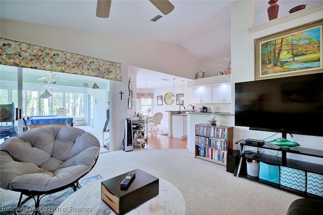 living room with vaulted ceiling, ceiling fan, light colored carpet, and plenty of natural light