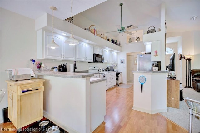 kitchen featuring decorative light fixtures, kitchen peninsula, light wood-type flooring, white cabinets, and stainless steel fridge