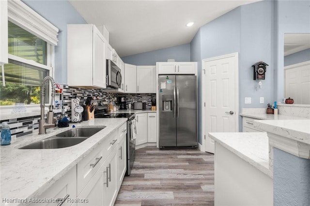 kitchen with backsplash, light wood-style floors, appliances with stainless steel finishes, and a sink