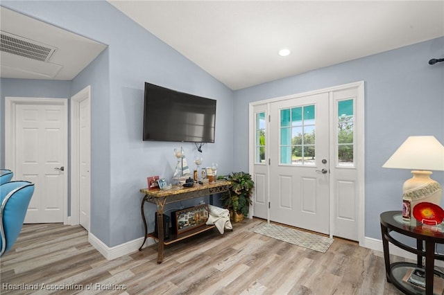 entryway with lofted ceiling, baseboards, wood finished floors, and visible vents