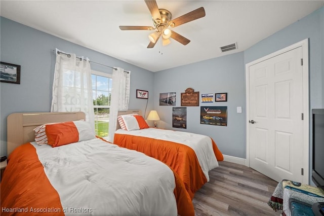 bedroom with wood finished floors, visible vents, baseboards, and ceiling fan