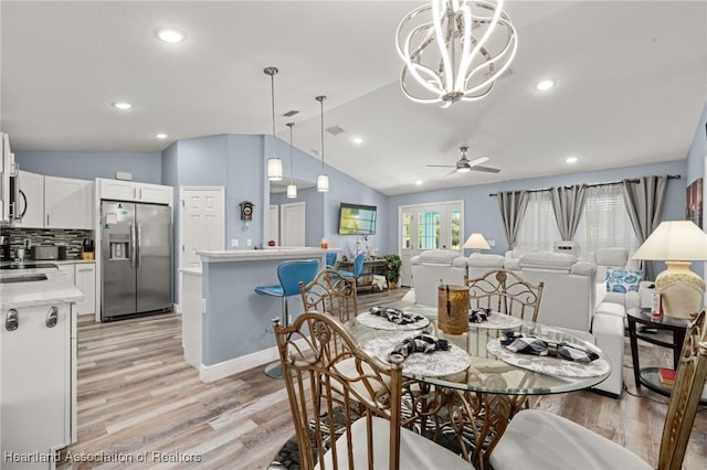 dining space featuring lofted ceiling, light wood finished floors, recessed lighting, and ceiling fan with notable chandelier
