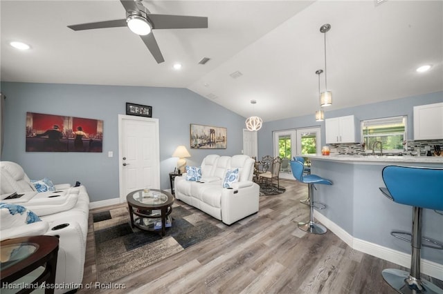 living area featuring vaulted ceiling, visible vents, baseboards, a ceiling fan, and wood finished floors