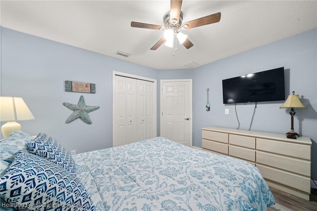 bedroom featuring wood finished floors, visible vents, a closet, and a ceiling fan