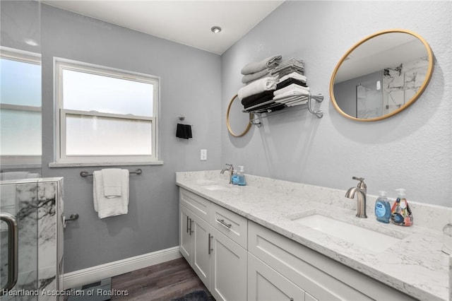 bathroom featuring baseboards, a shower with door, wood finished floors, and a sink