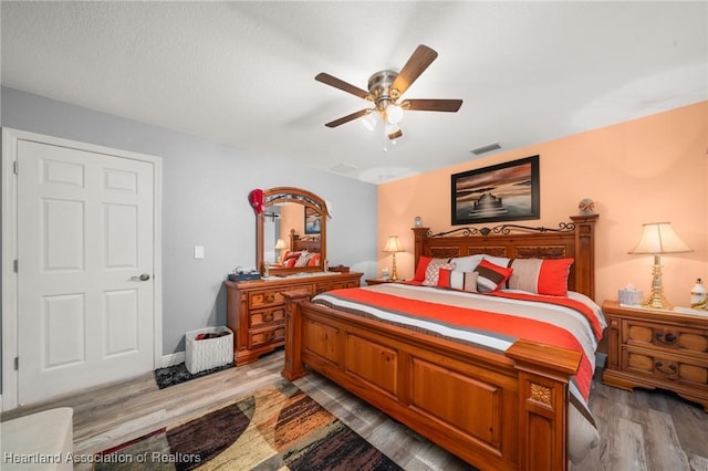 bedroom with ceiling fan, wood finished floors, and visible vents