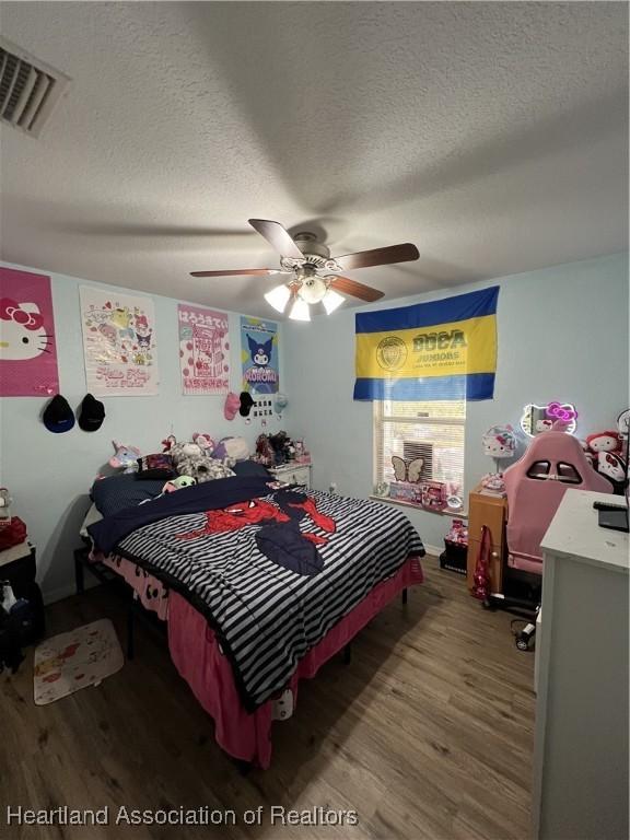 bedroom featuring ceiling fan, hardwood / wood-style floors, and a textured ceiling