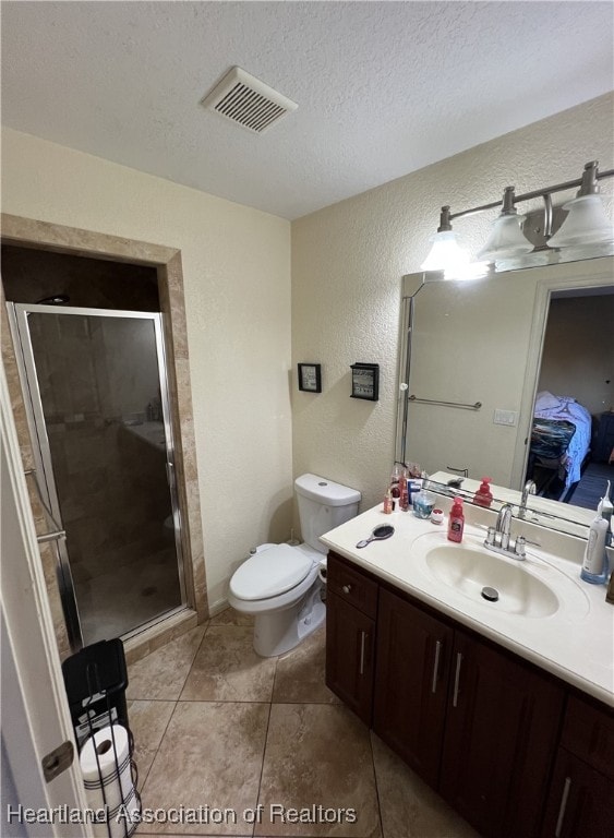 bathroom with vanity, toilet, a shower with door, and a textured ceiling