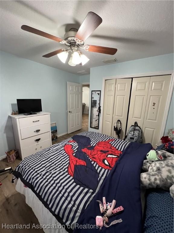 bedroom with hardwood / wood-style flooring, ceiling fan, a closet, and a textured ceiling