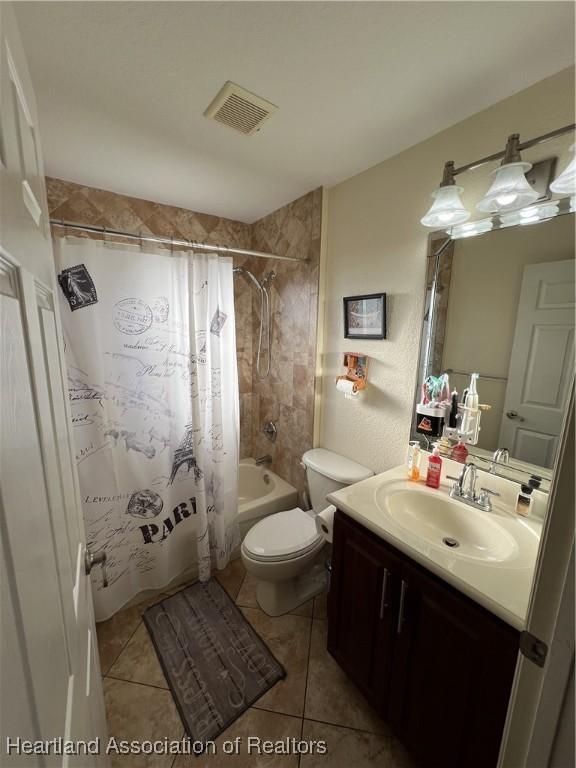 full bathroom featuring toilet, tile patterned floors, vanity, and shower / bathtub combination with curtain