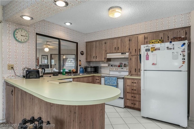 kitchen with light tile patterned flooring, a textured ceiling, white appliances, and kitchen peninsula