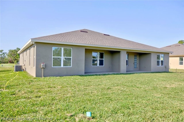 back of property featuring central AC unit and a yard