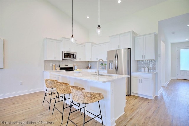 kitchen featuring stainless steel appliances, white cabinetry, sink, and a kitchen island with sink