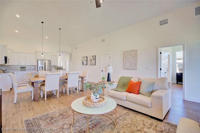 living room featuring a towering ceiling and light wood-type flooring