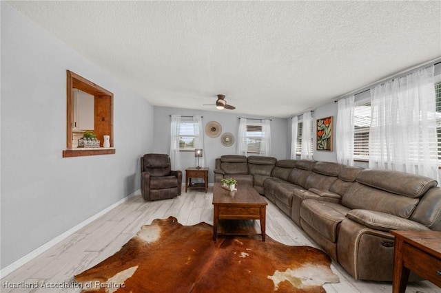 living room featuring baseboards, wood finished floors, a ceiling fan, and a textured ceiling