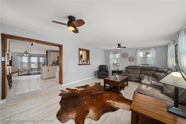 living area with a healthy amount of sunlight, ceiling fan, and light wood finished floors